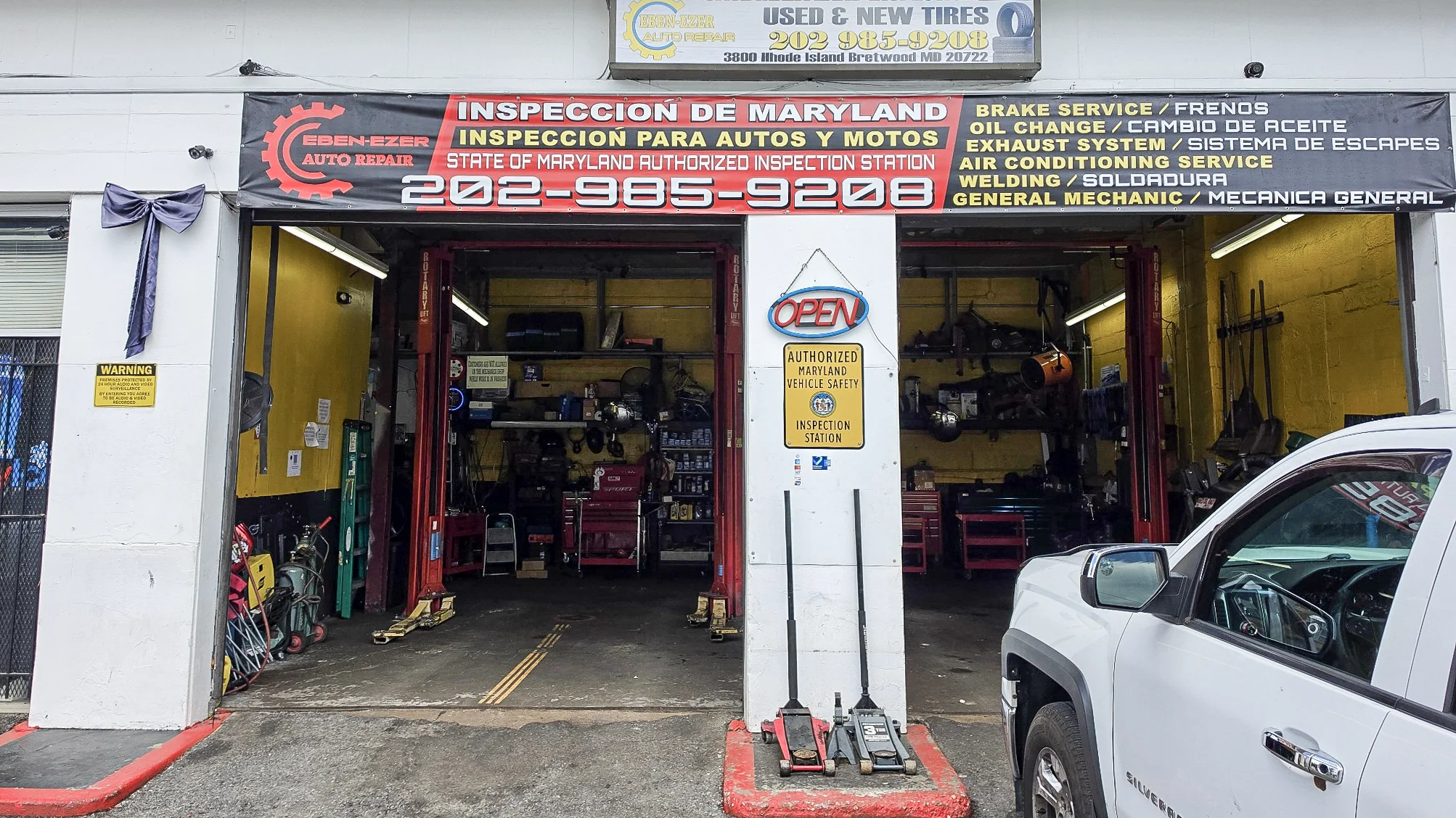 Full front view of Ebenezer Auto Repair, its Maryland inspection sign and two open service bays